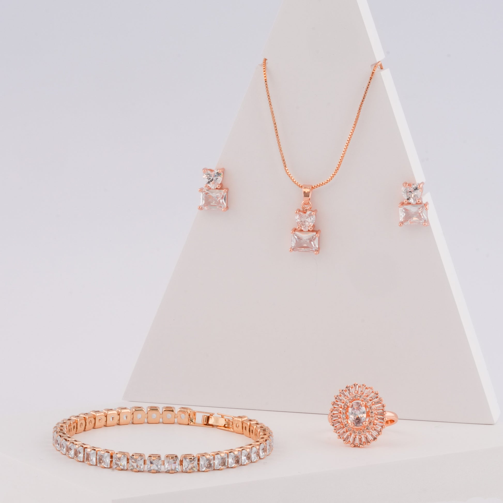 Rose gold jewelry set with necklace, earrings, and bracelet on a white background