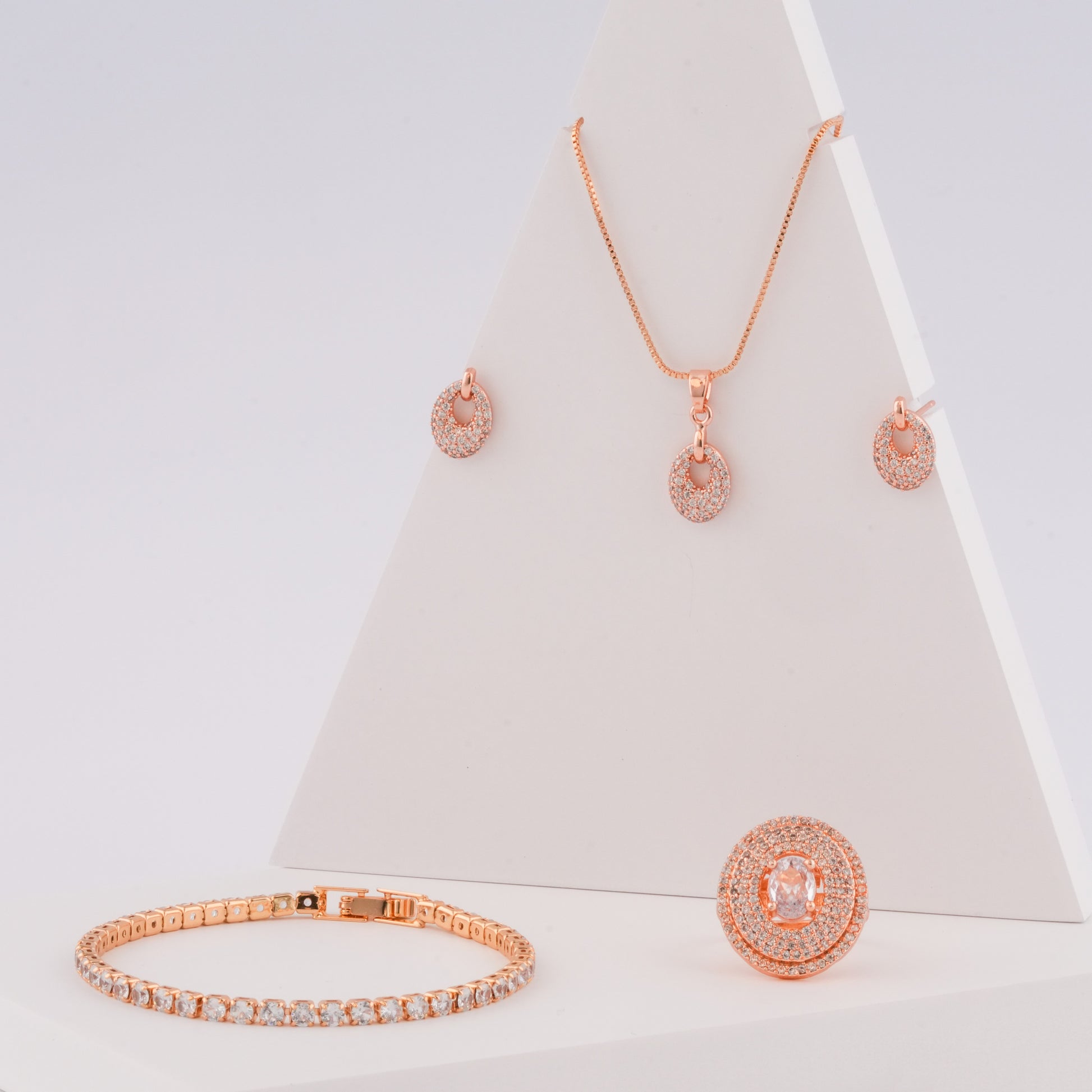 Rose gold jewelry set including necklace, earrings, bracelet, and ring on a white background