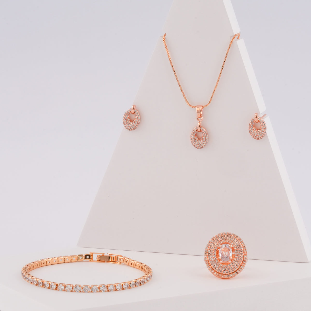 Rose gold jewelry set including necklace, earrings, bracelet, and ring on a white background