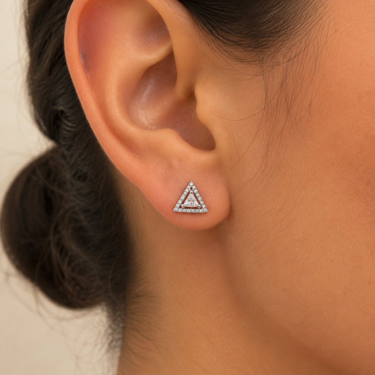 Close on-ear scale view of silver triangular stud earring