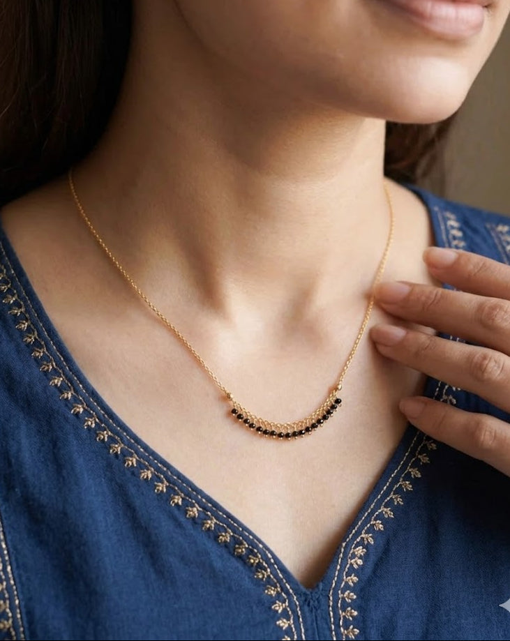 Woman wearing a delicate gold necklace with a blurred background