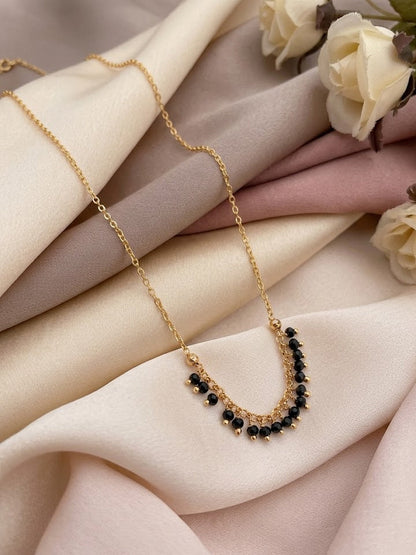 Gold necklace with black beads on a soft fabric background