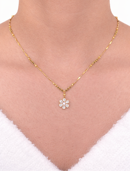 Gold necklace with a floral pendant on a person's neck against a white background