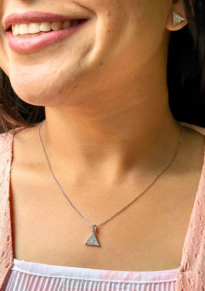 Close-up of a person wearing a necklace with a triangle silver pendant.