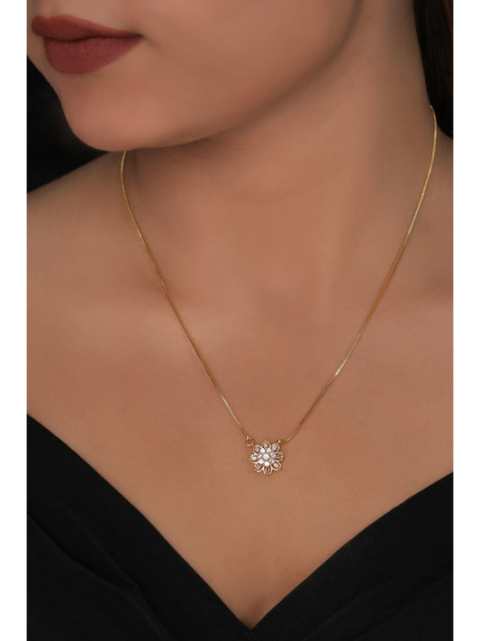 Gold necklace with a floral pendant on a model wearing a black dress.