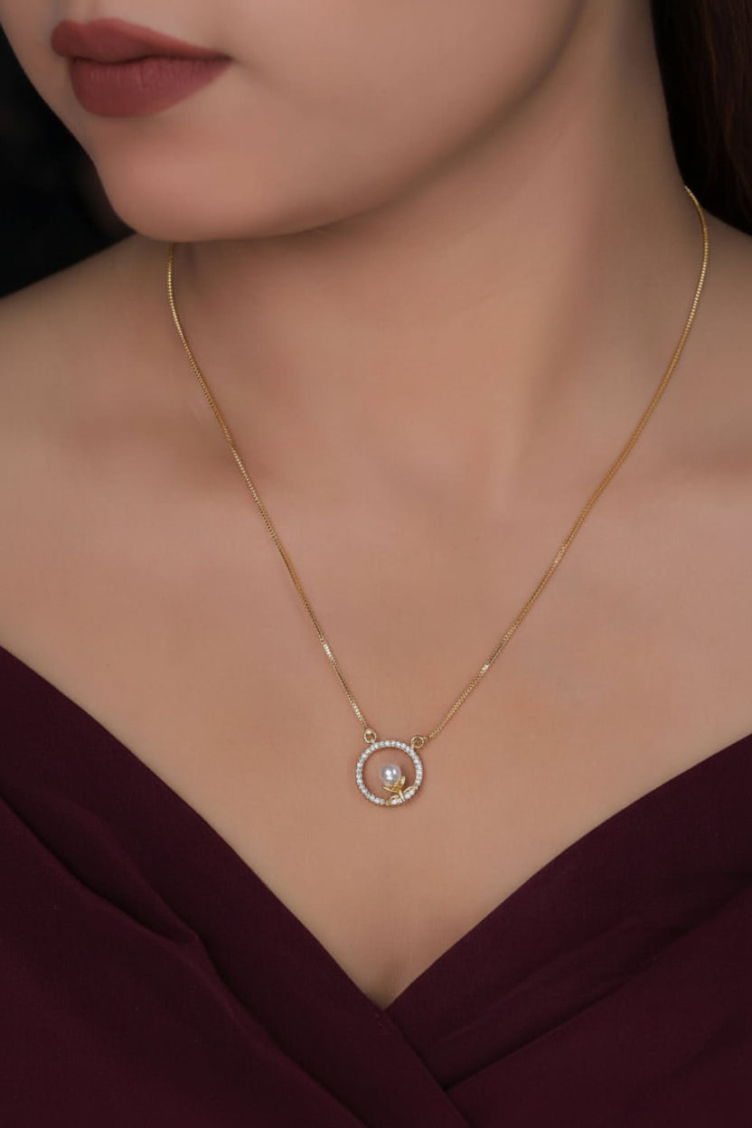Gold necklace with a pendant on a model wearing a black top