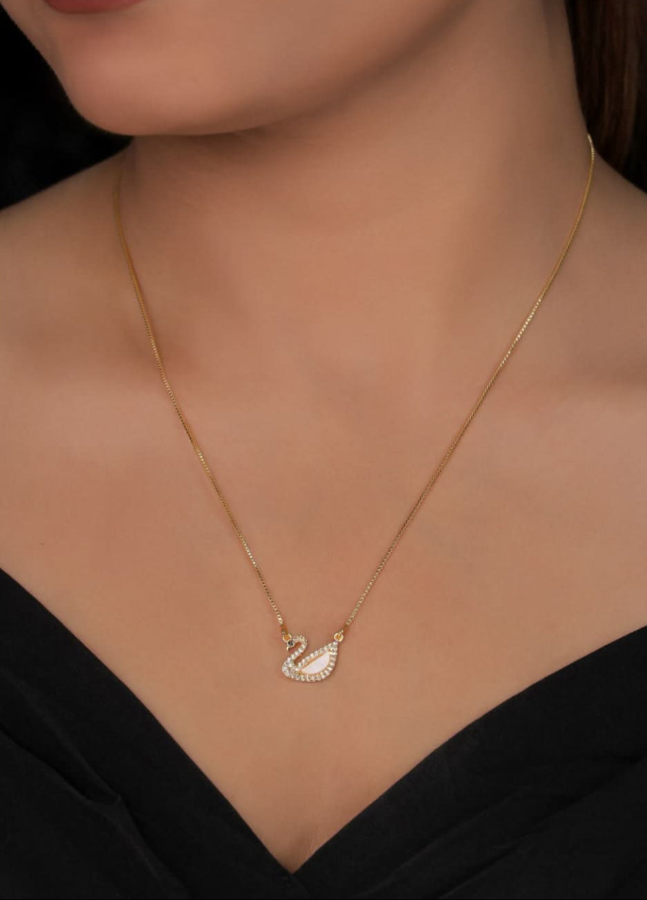Gold necklace with a swan pendant worn by a model