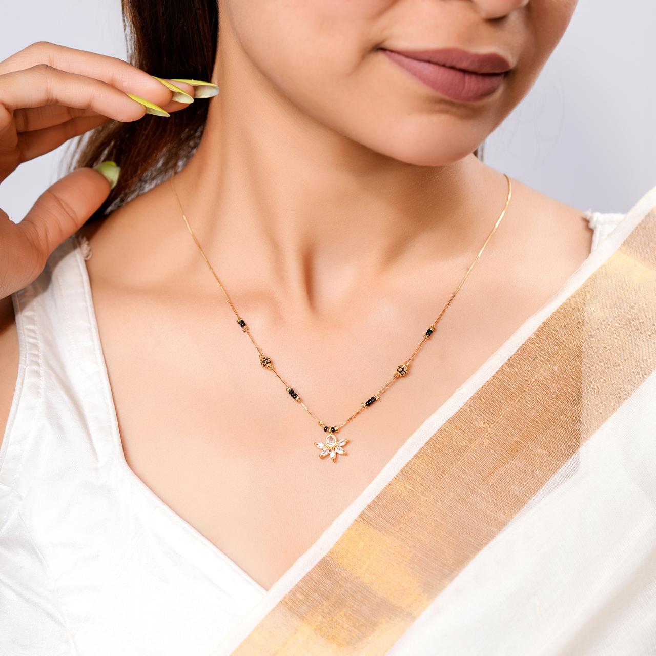 Woman wearing a gold necklace with a white blouse