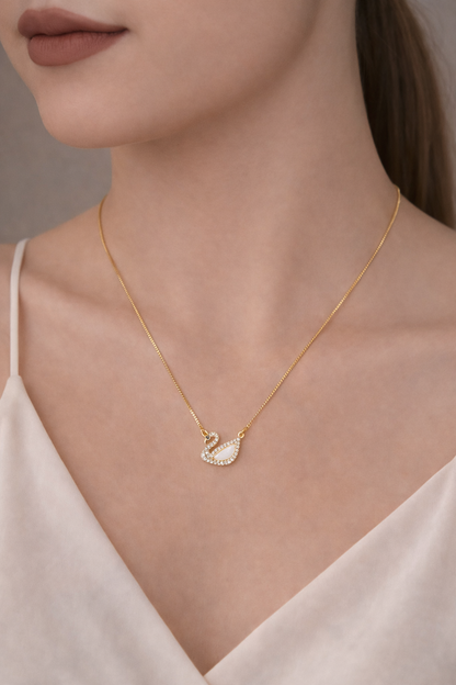 Gold necklace with a swan pendant worn by a model against a neutral background