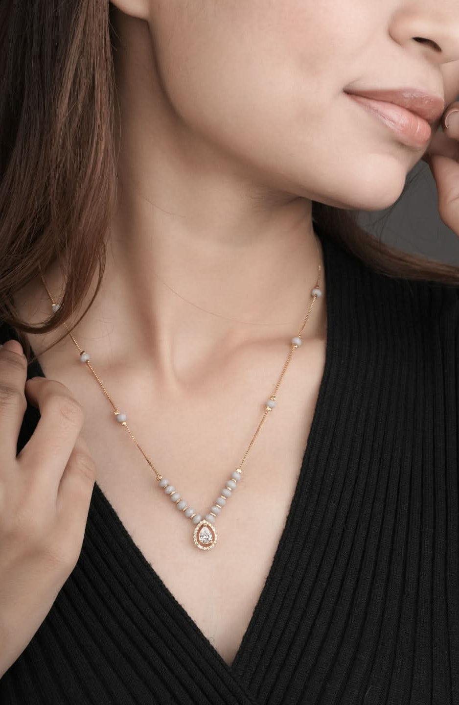 Necklace with a heart-shaped pendant worn by a person against a neutral background