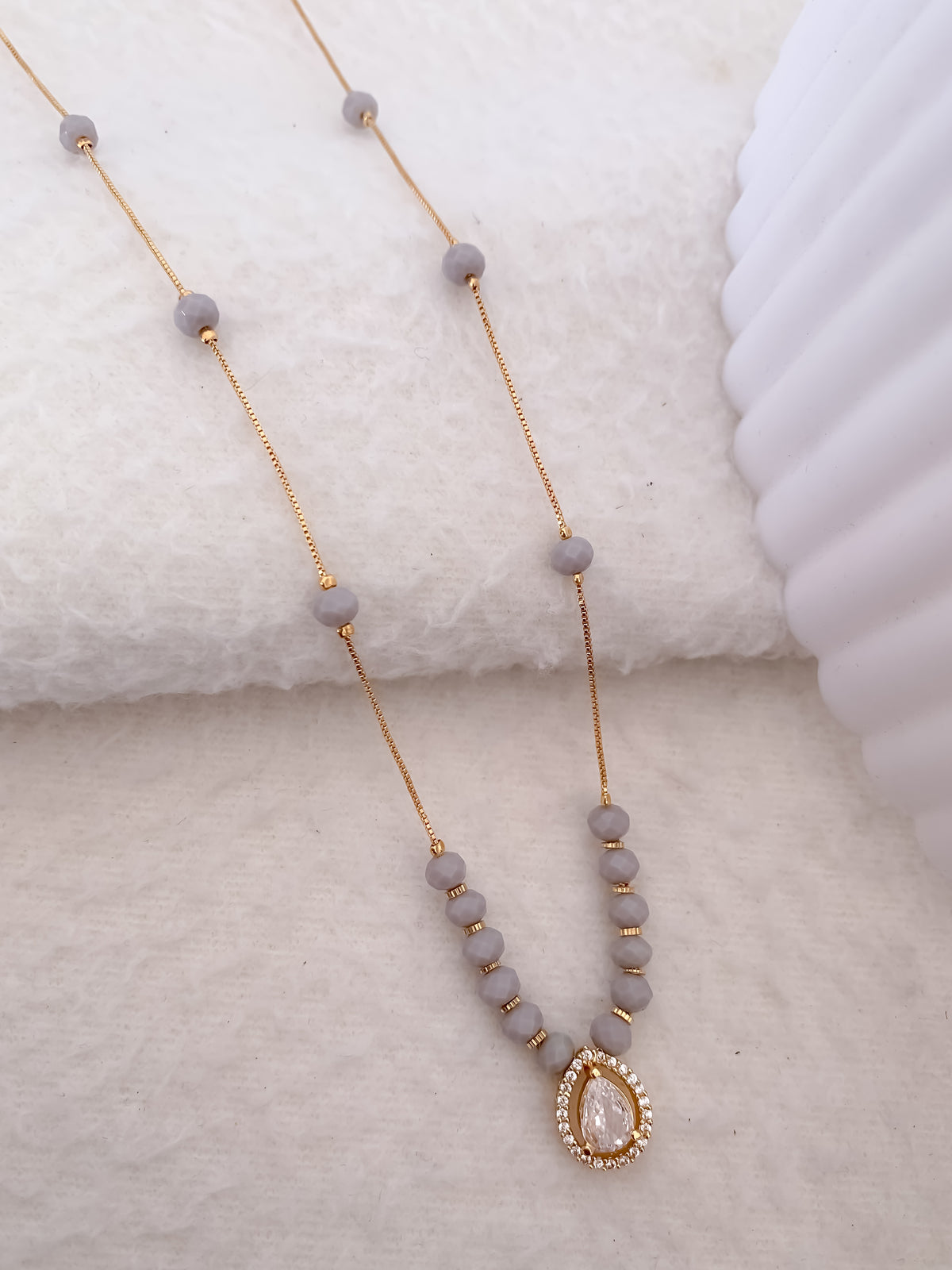 Necklace with gray beads and a gold accent on a textured surface