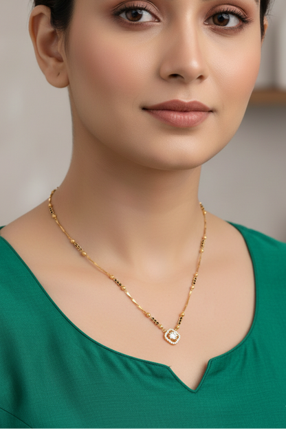 Woman wearing a gold necklace with a green top against a neutral background