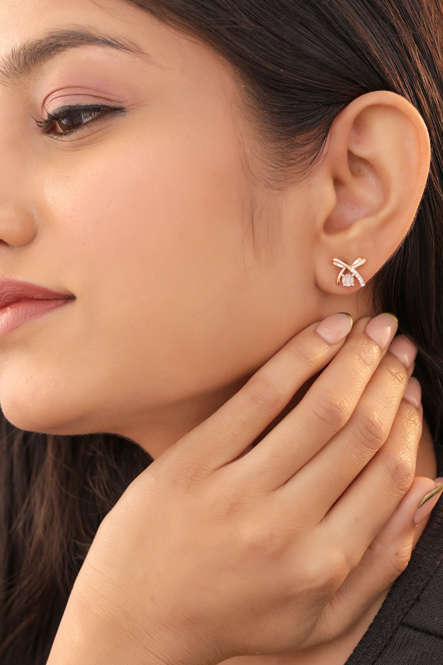 Close-up of a woman wearing a gold bow-shaped earring.