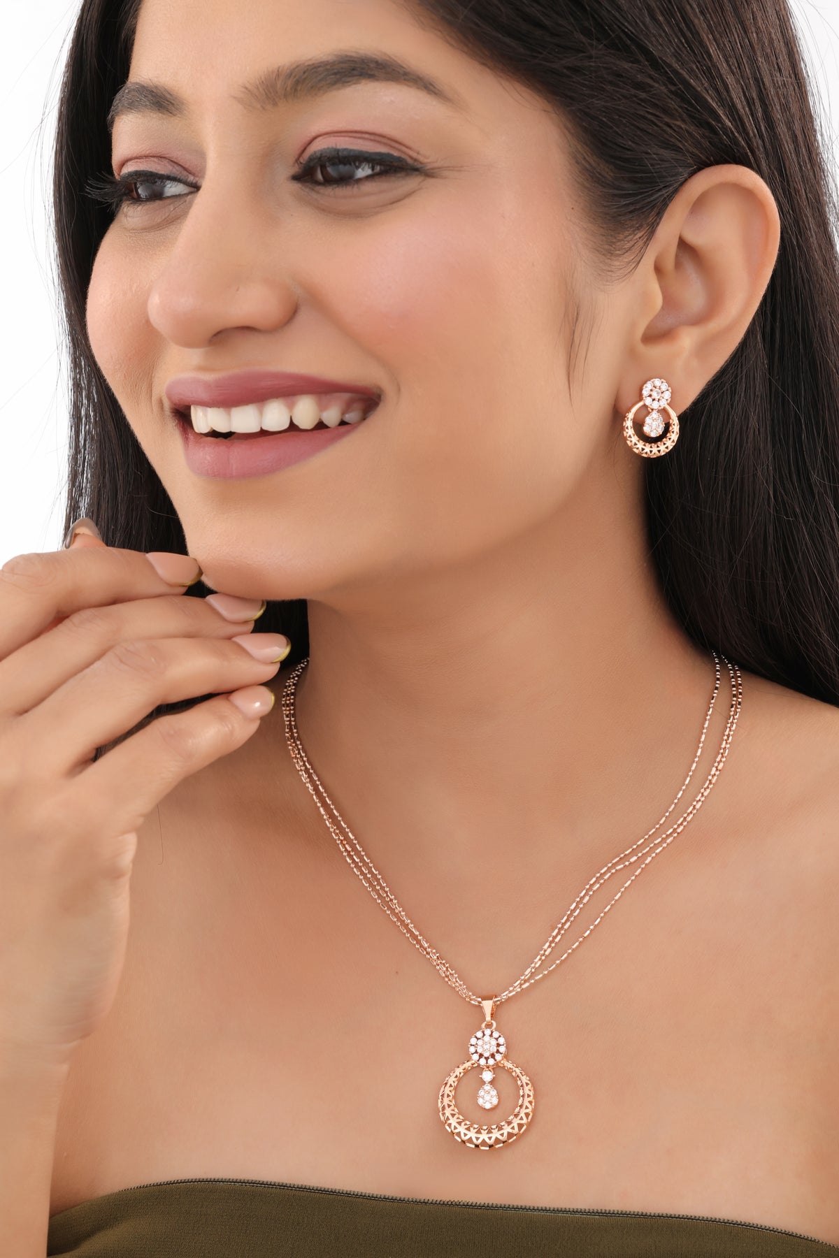 Woman wearing a rose gold necklace and earrings with a white background