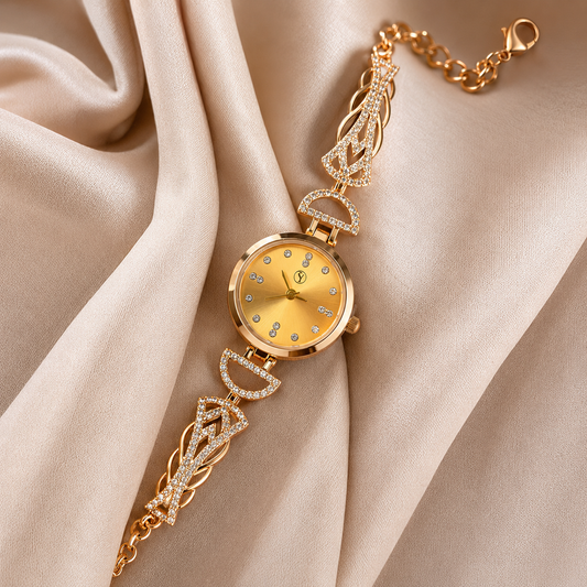 A gold-tone watch with a round dial and matching bracelet, decorated with small clear rhinestones, displayed on draped champagne-colored satin fabric.