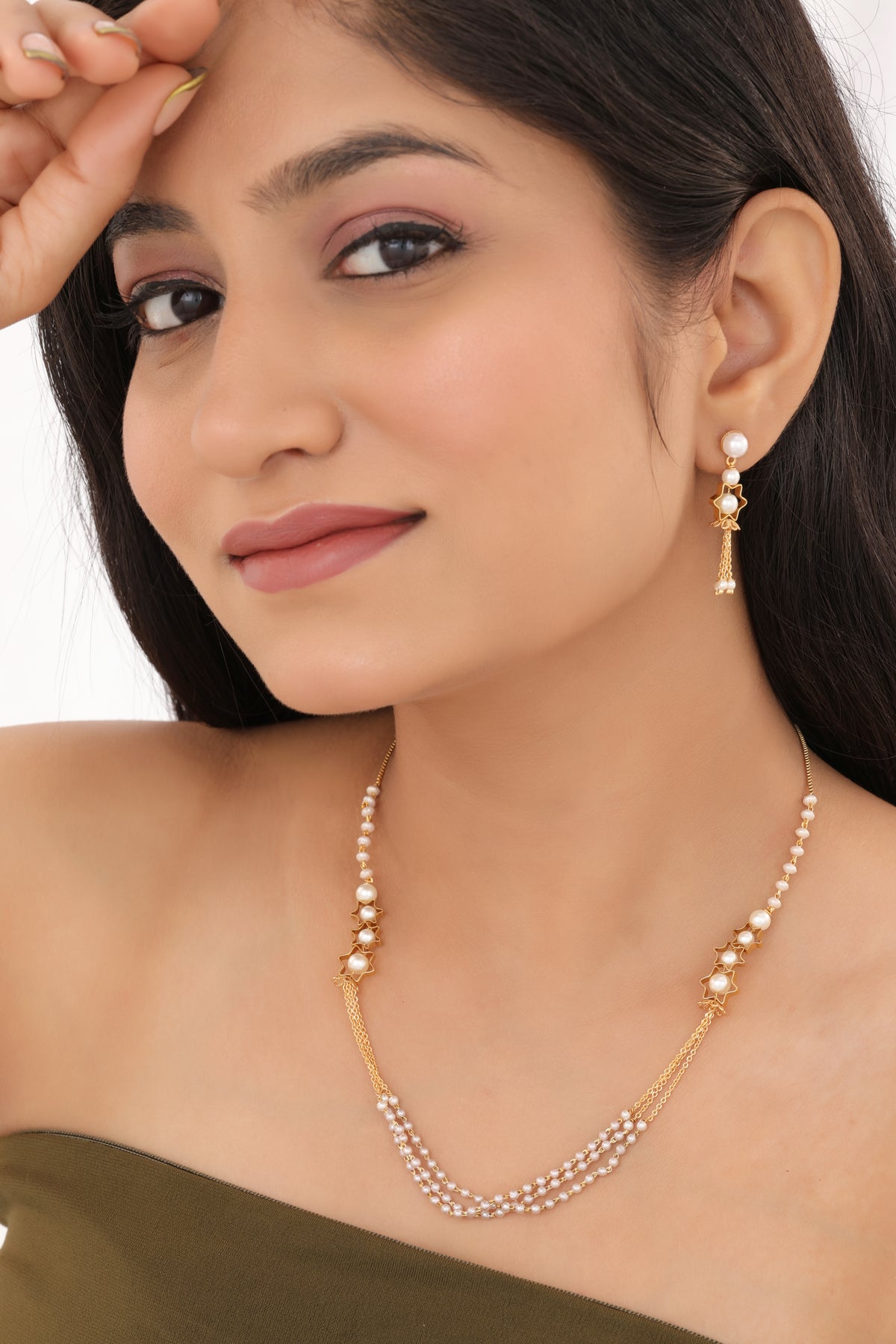 Woman wearing a pearl necklace and earrings on a white background