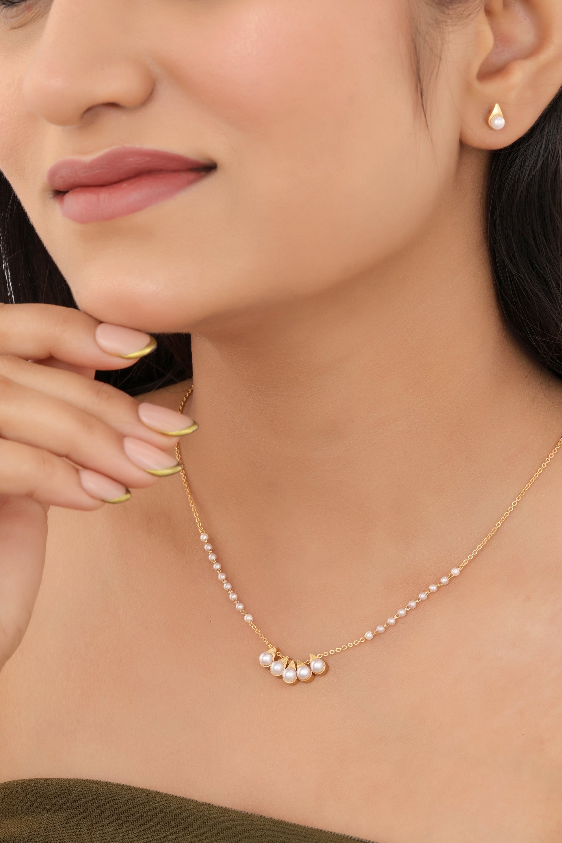 Woman wearing a gold necklace and earrings on a white background