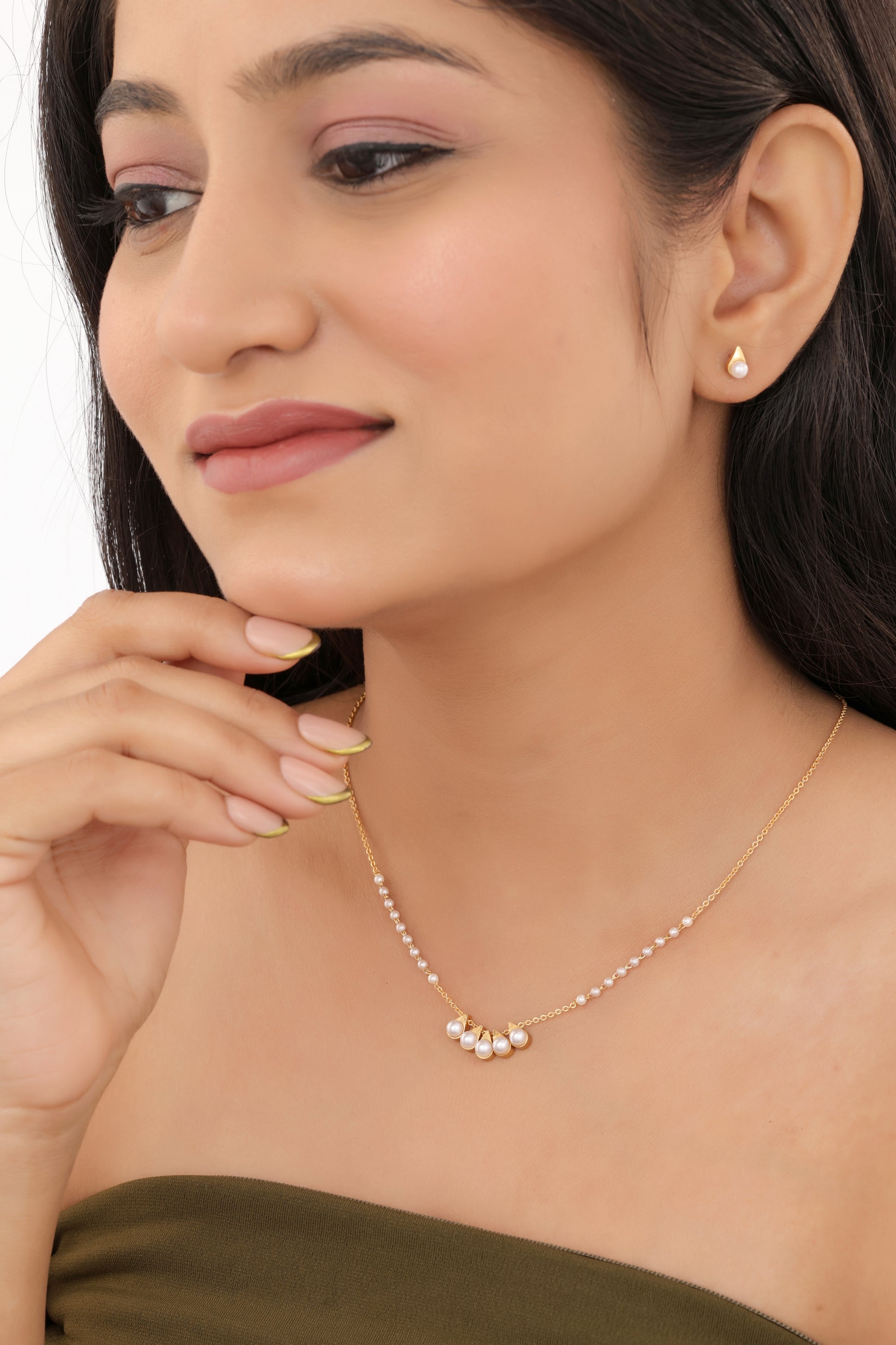 Woman wearing a gold necklace and earrings on a white background