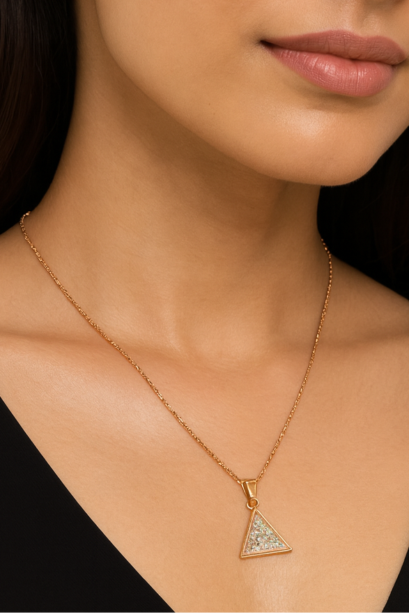Woman wearing a gold necklace and earrings against a neutral background