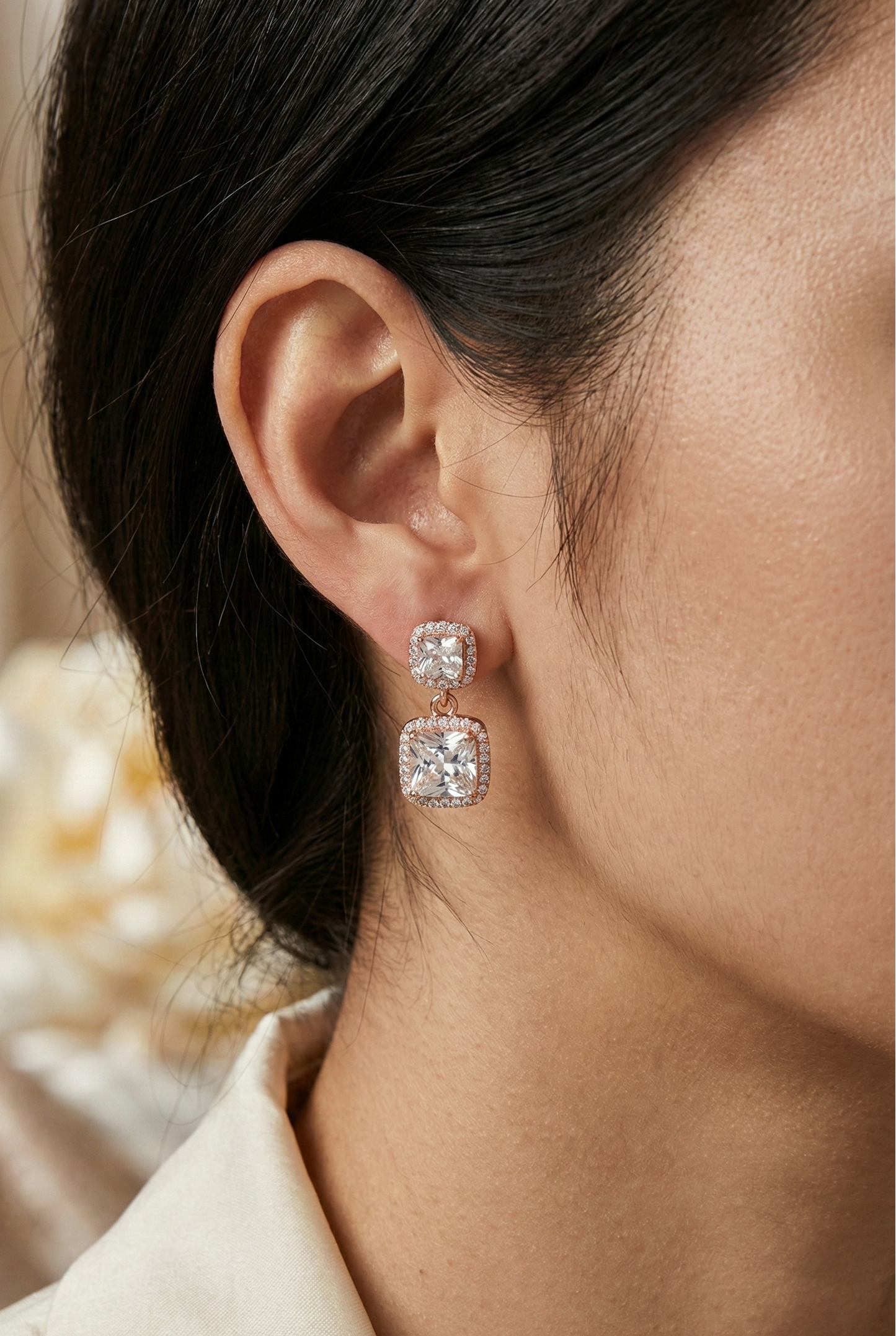 Close-up of a person wearing a diamond earring with a soft blurred background