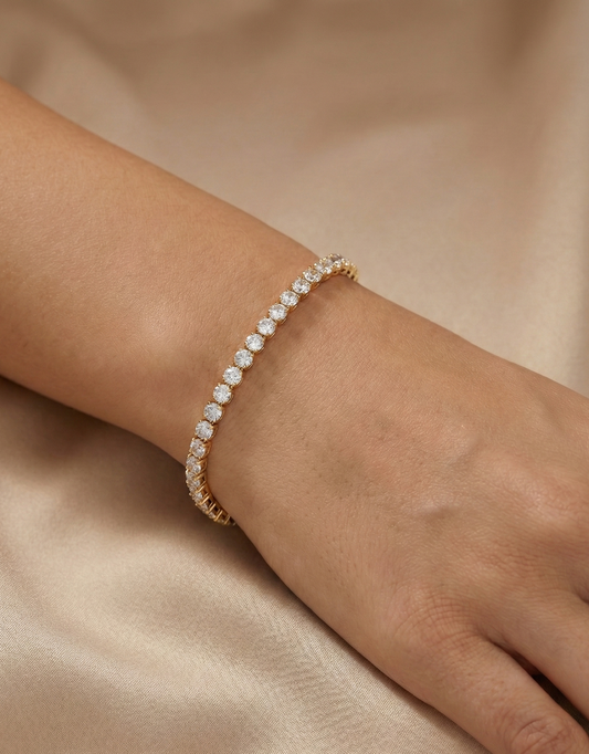 Gold tenis bracelet with diamonds on a wrist against a beige background | Belleza Jewels