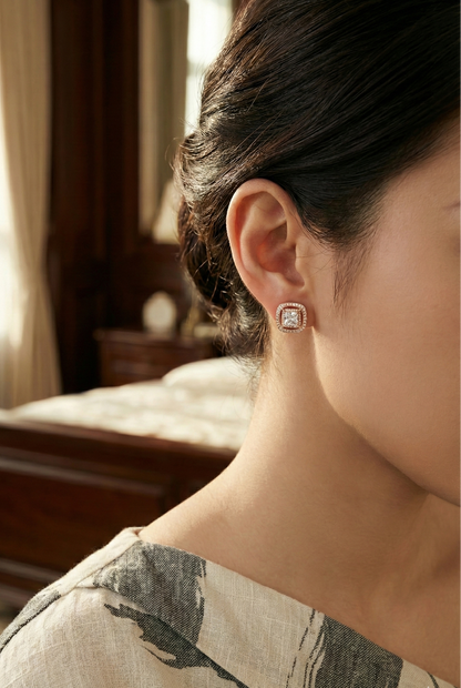 Close-up of a person wearing a diamond earring in a softly lit room.