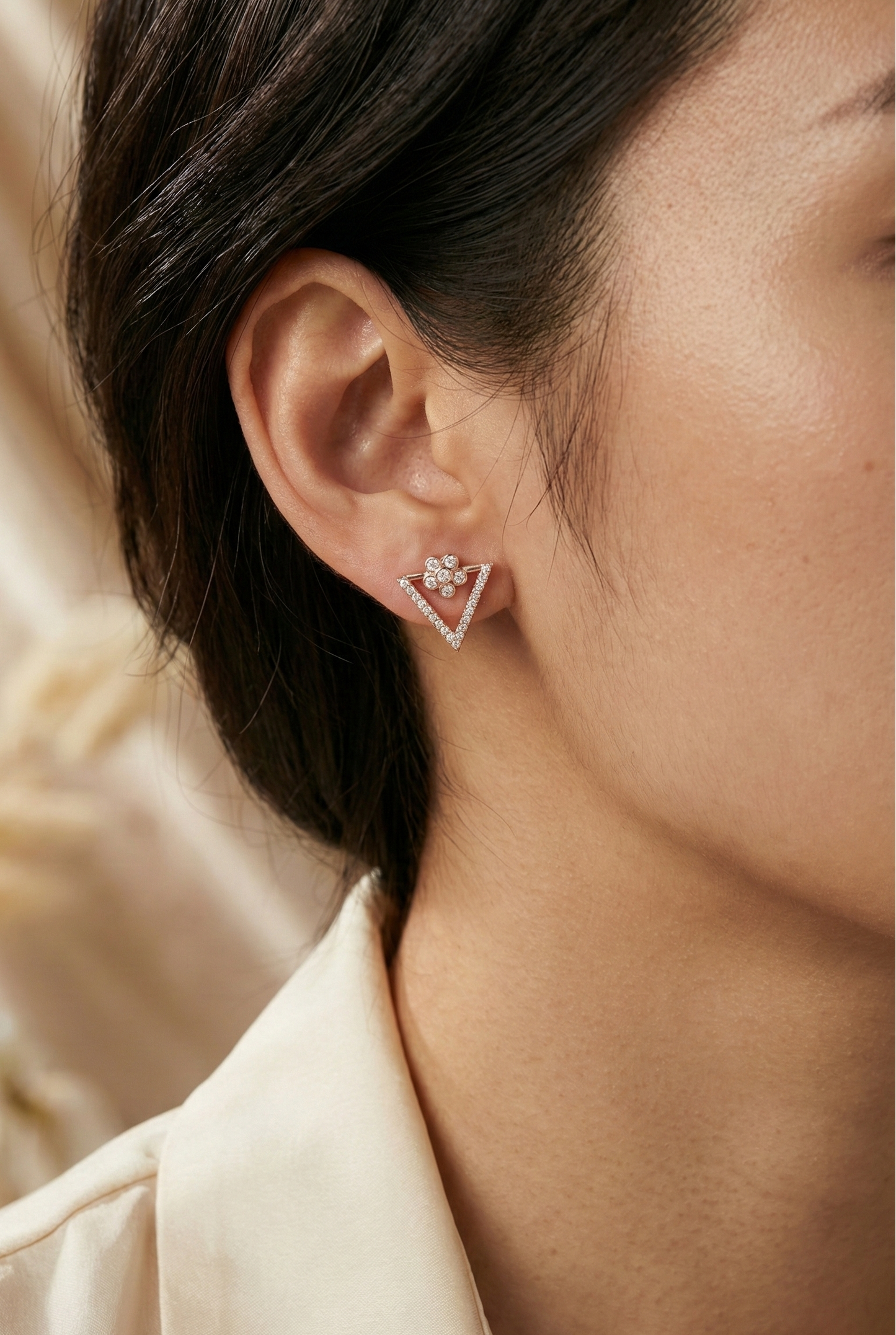 Close-up of a person wearing a diamond earring with a soft background