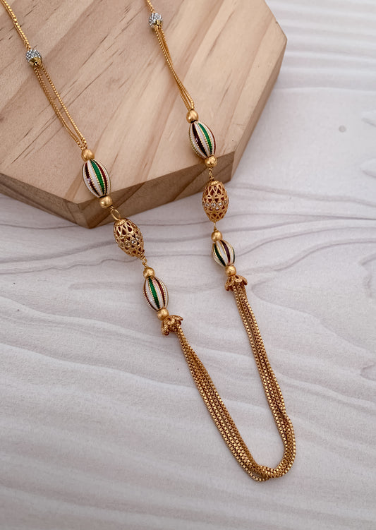 Gold necklace with decorative beads on a light wooden block