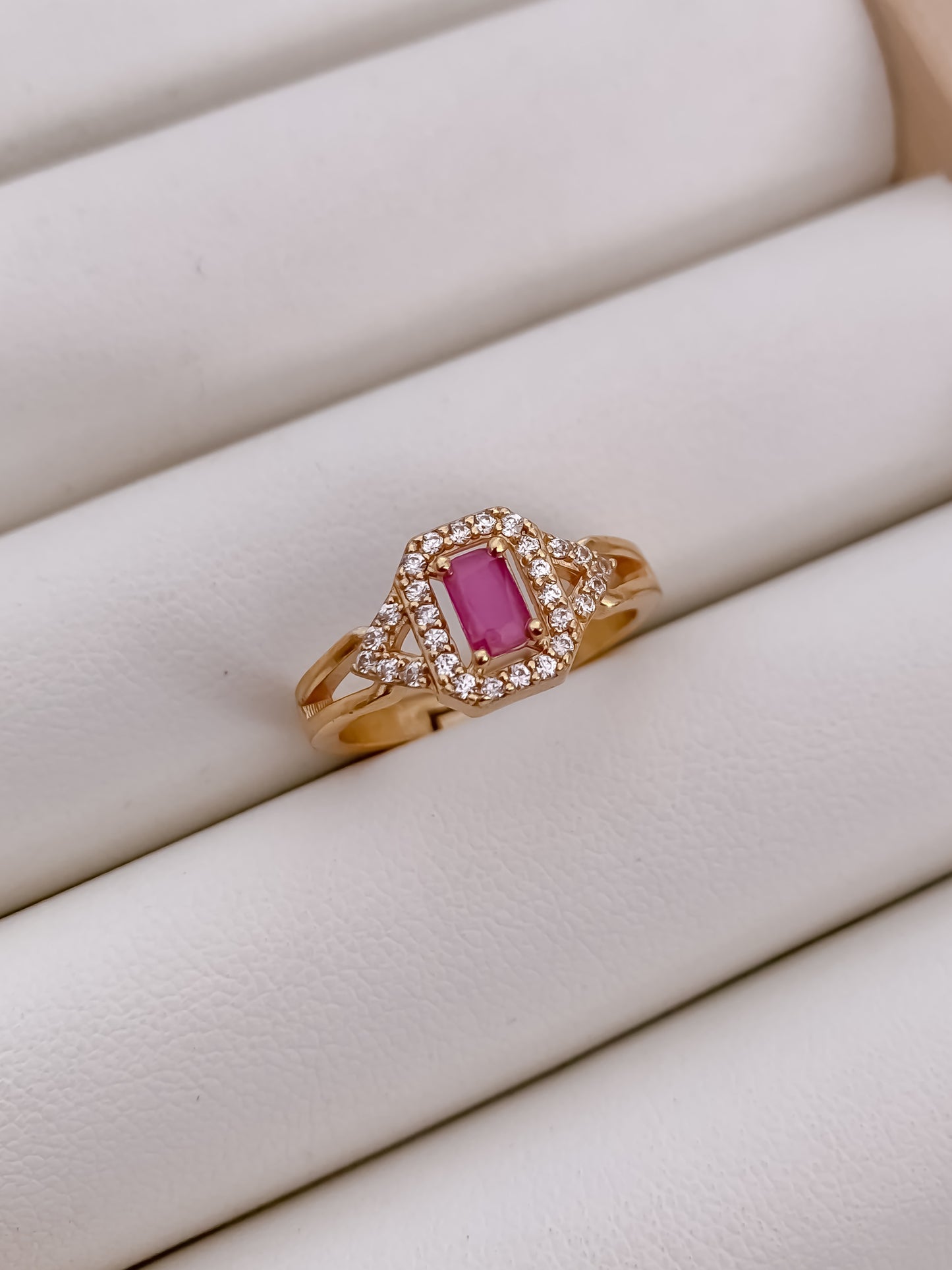 Rose gold ring with a pink gemstone on a white surface