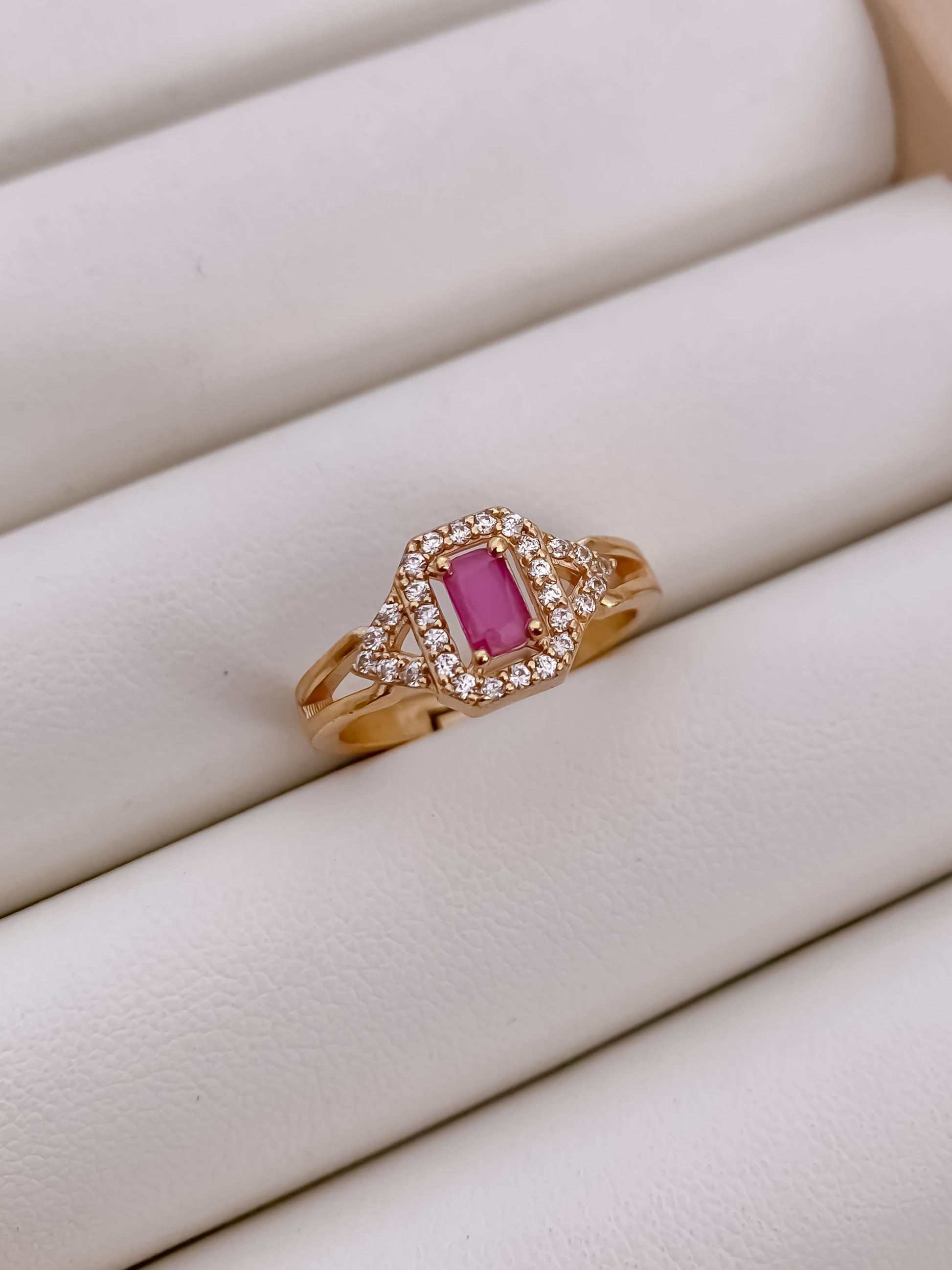 Rose gold ring with a pink gemstone on a white surface