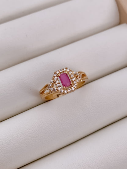 Rose gold ring with a pink gemstone on a white surface