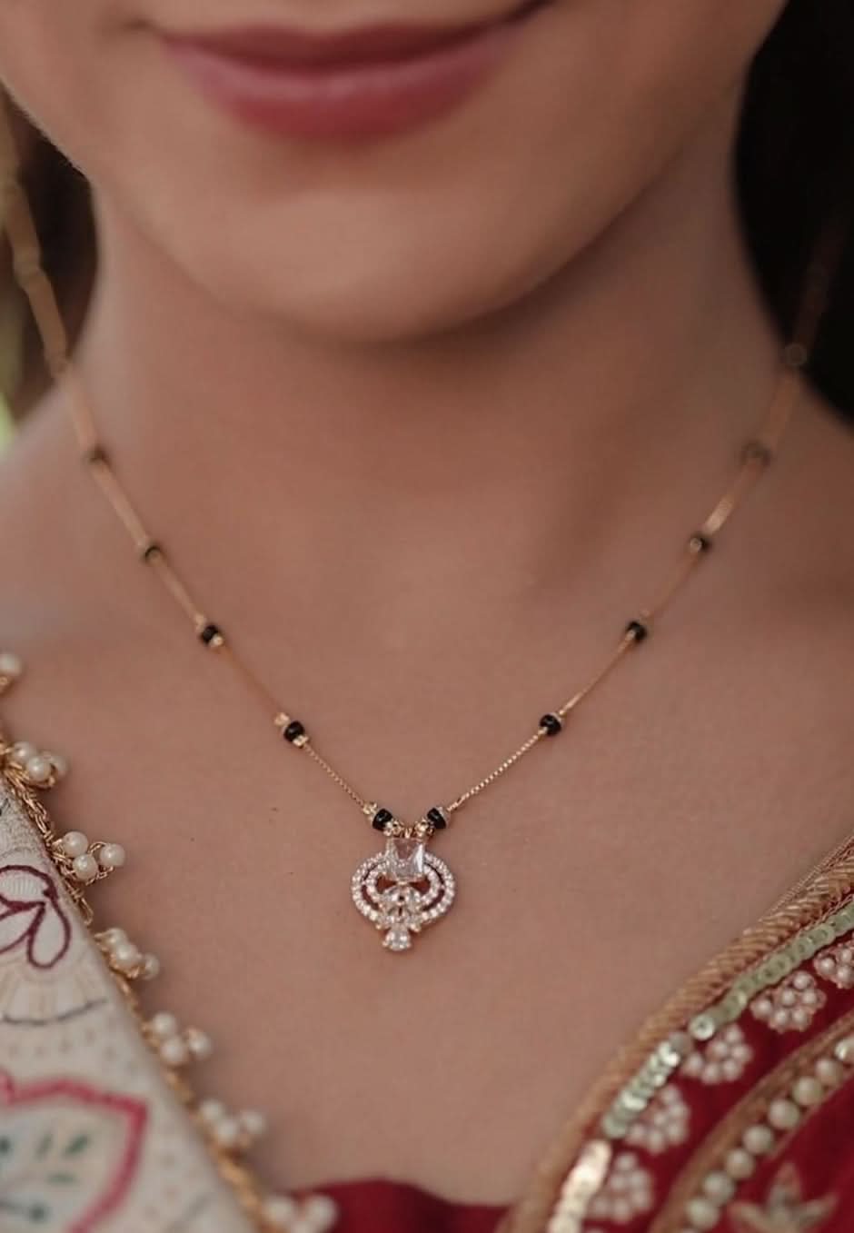 Close-up of a woman wearing a delicate and trendy Mangalsutra with a red and gold traditional outfit.