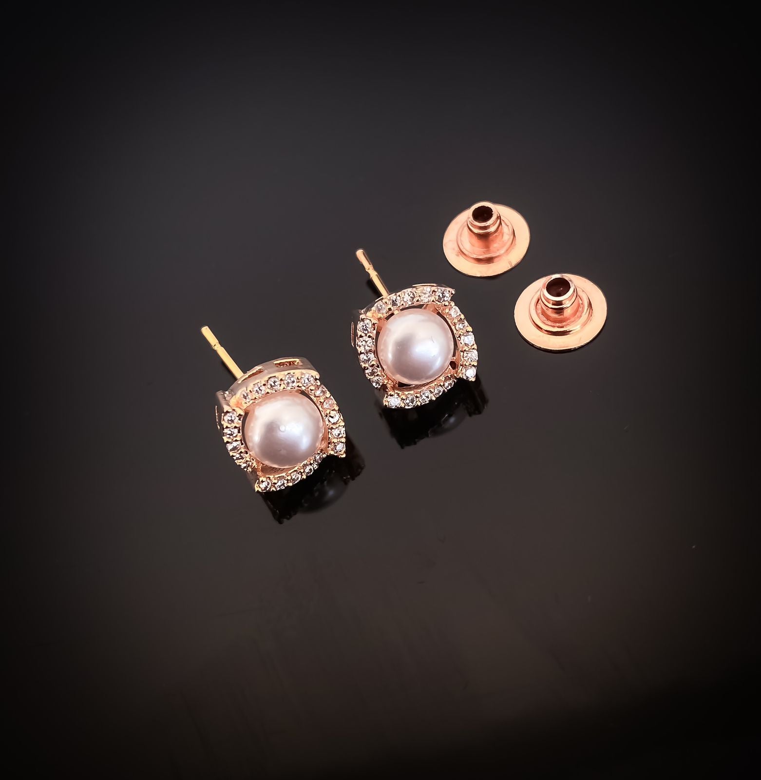 Pair of pearl earrings with rose gold settings on a black background