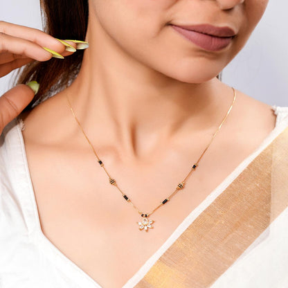 Woman wearing a gold necklace with a white blouse