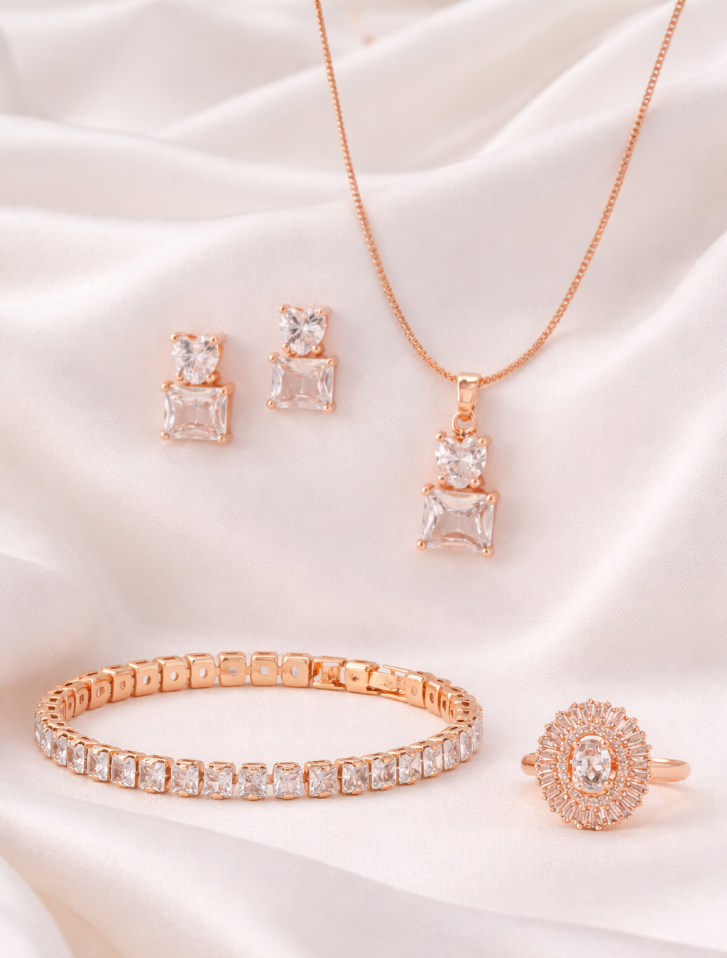 Rose gold jewelry set including necklace, earrings, bracelet, and ring on a white satin background