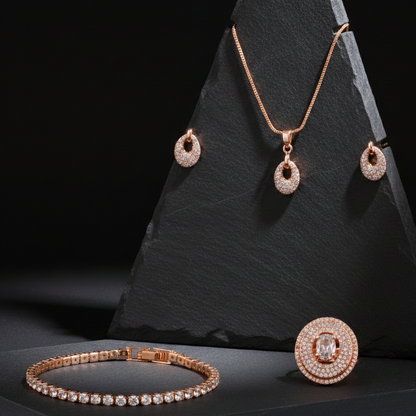 Rose gold jewelry set including necklace, earrings, ring, and bracelet on a black stone stand.