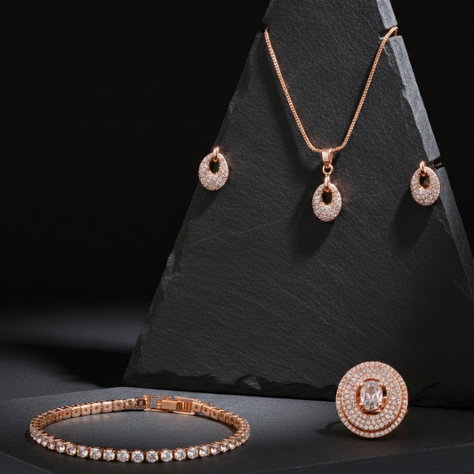 Rose gold jewelry set including necklace, earrings, ring, and bracelet on a black stone stand.