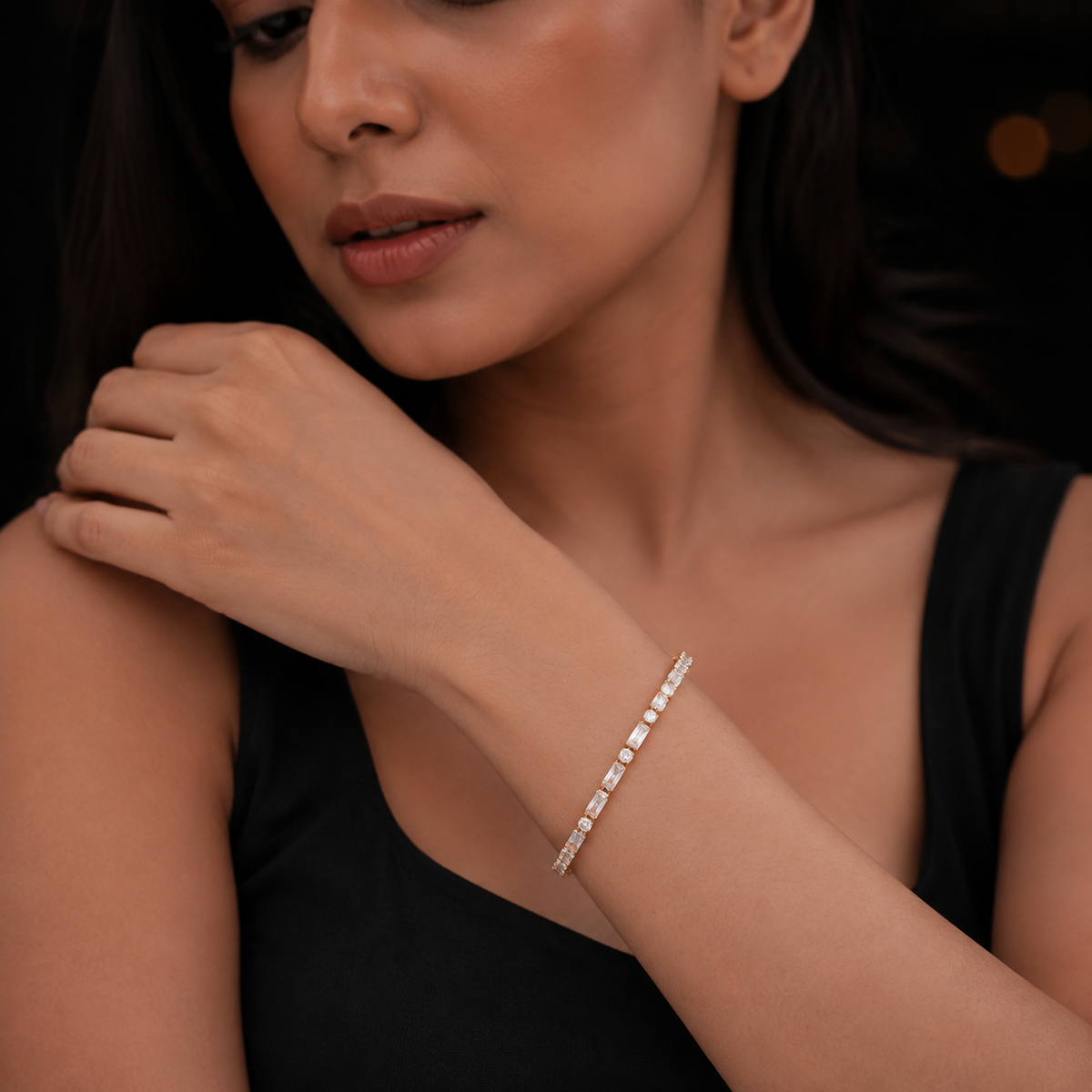 Woman in black wearing the gold baguette and round stone tennis bracelet