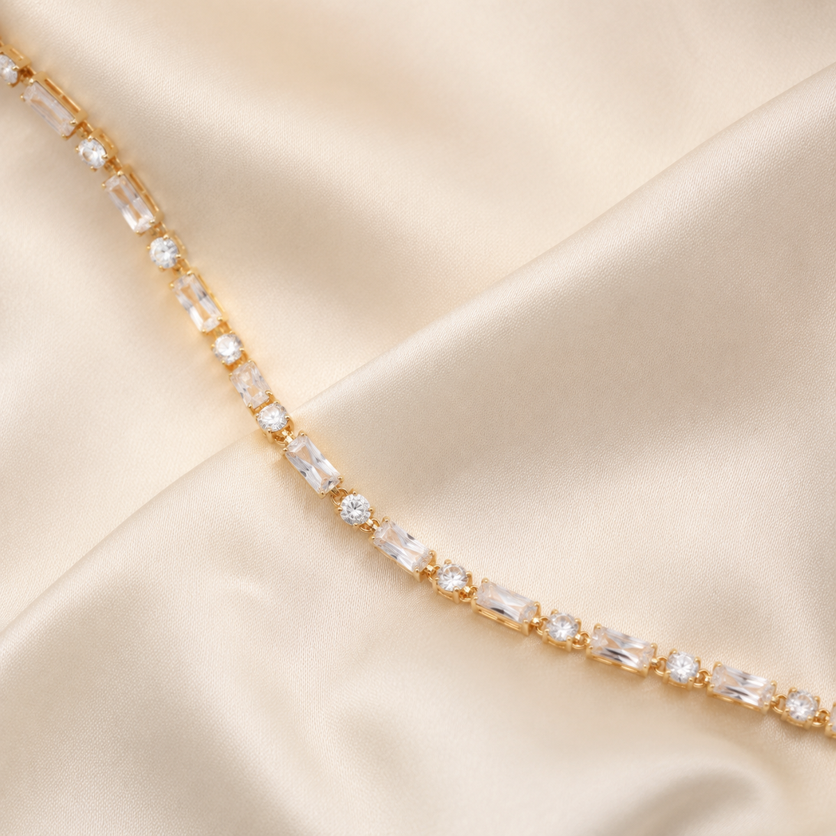 Gold baguette and round stone tennis bracelet styled on ivory silk