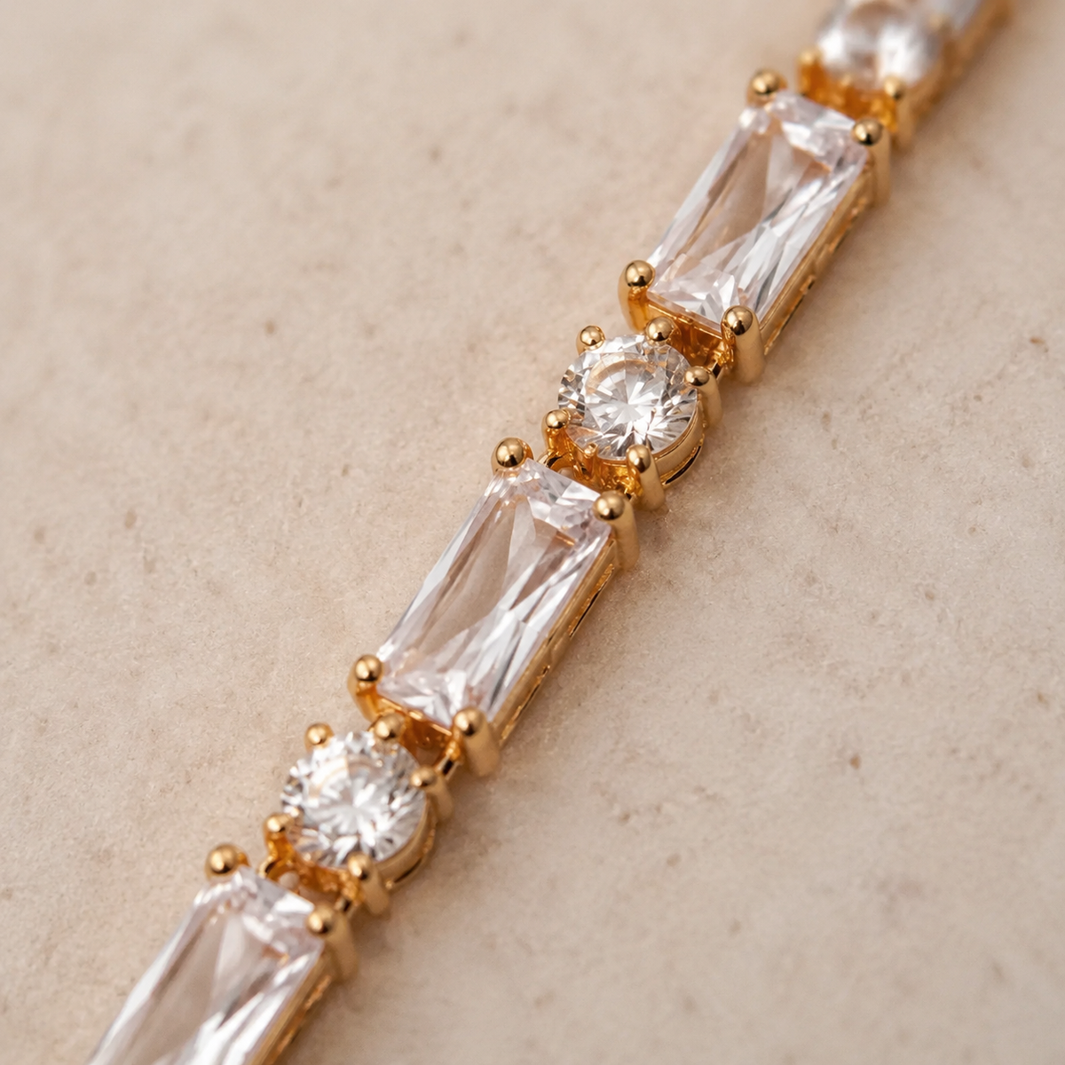 Macro detail of alternating baguette and round stones in the gold tennis bracelet