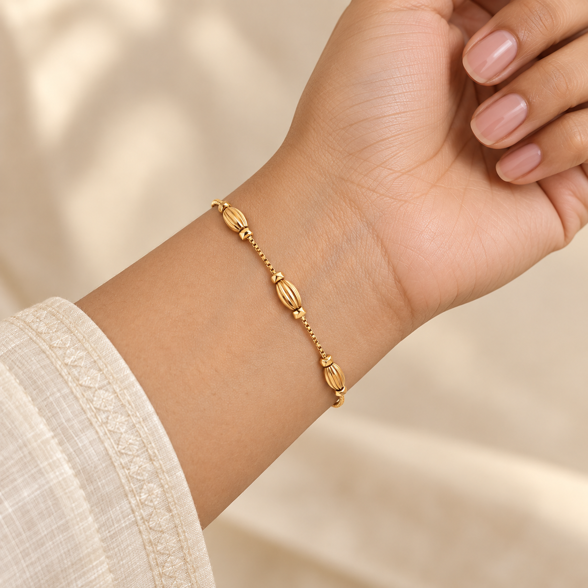 Sculpted oval charm gold-tone bracelet worn on wrist in daylight