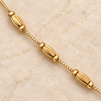 Close-up of three sculpted oval charms on gold-tone bracelet