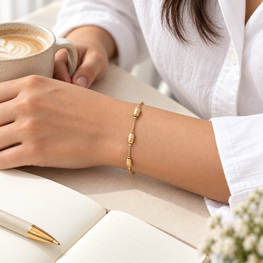 Textured oval bead gold-tone bracelet in coffee desk lifestyle