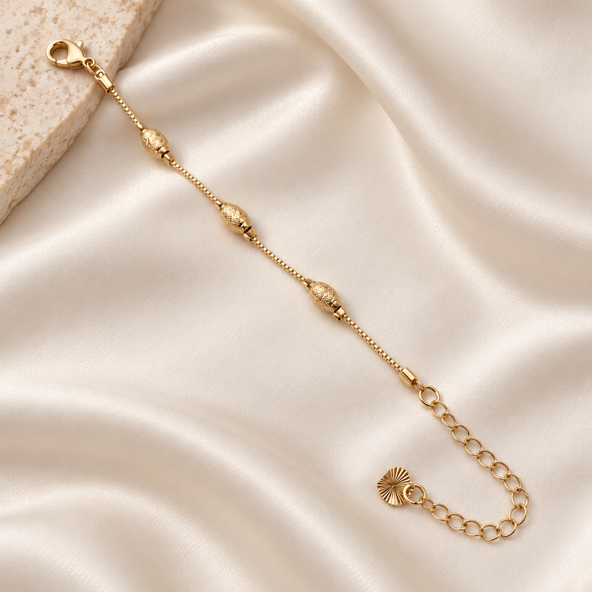 Textured oval bead gold-tone bracelet on ivory silk