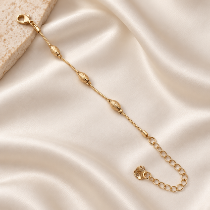 Textured oval bead gold-tone bracelet on ivory silk