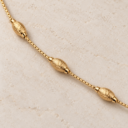 Close-up of three textured oval beads on gold-tone bracelet