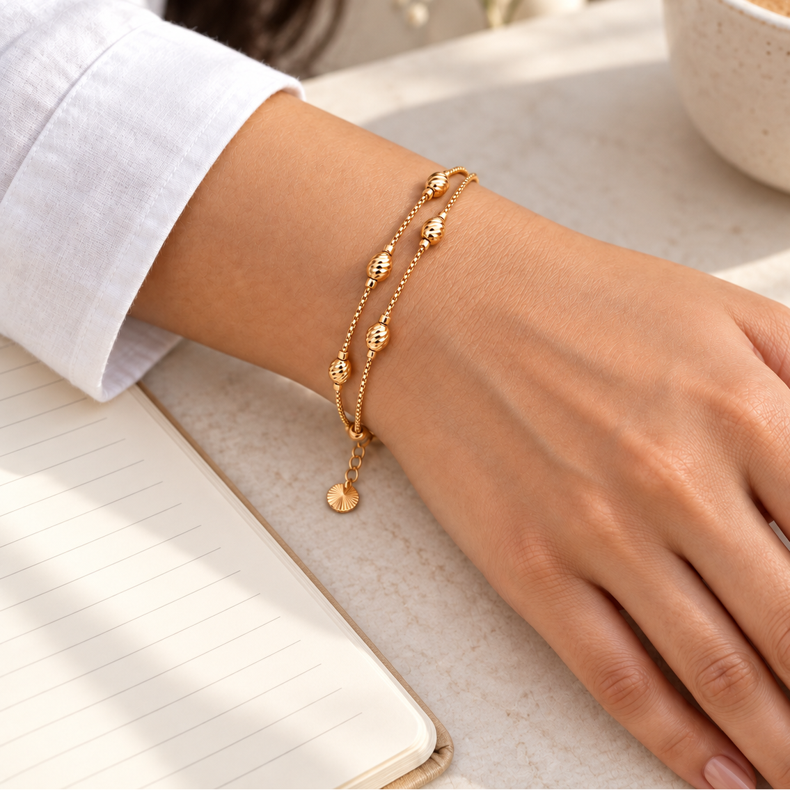Textured bead double-layer gold-tone bracelet in coffee desk lifestyle