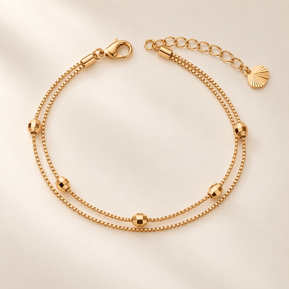 Faceted bead double-layer gold-tone bracelet on warm ivory