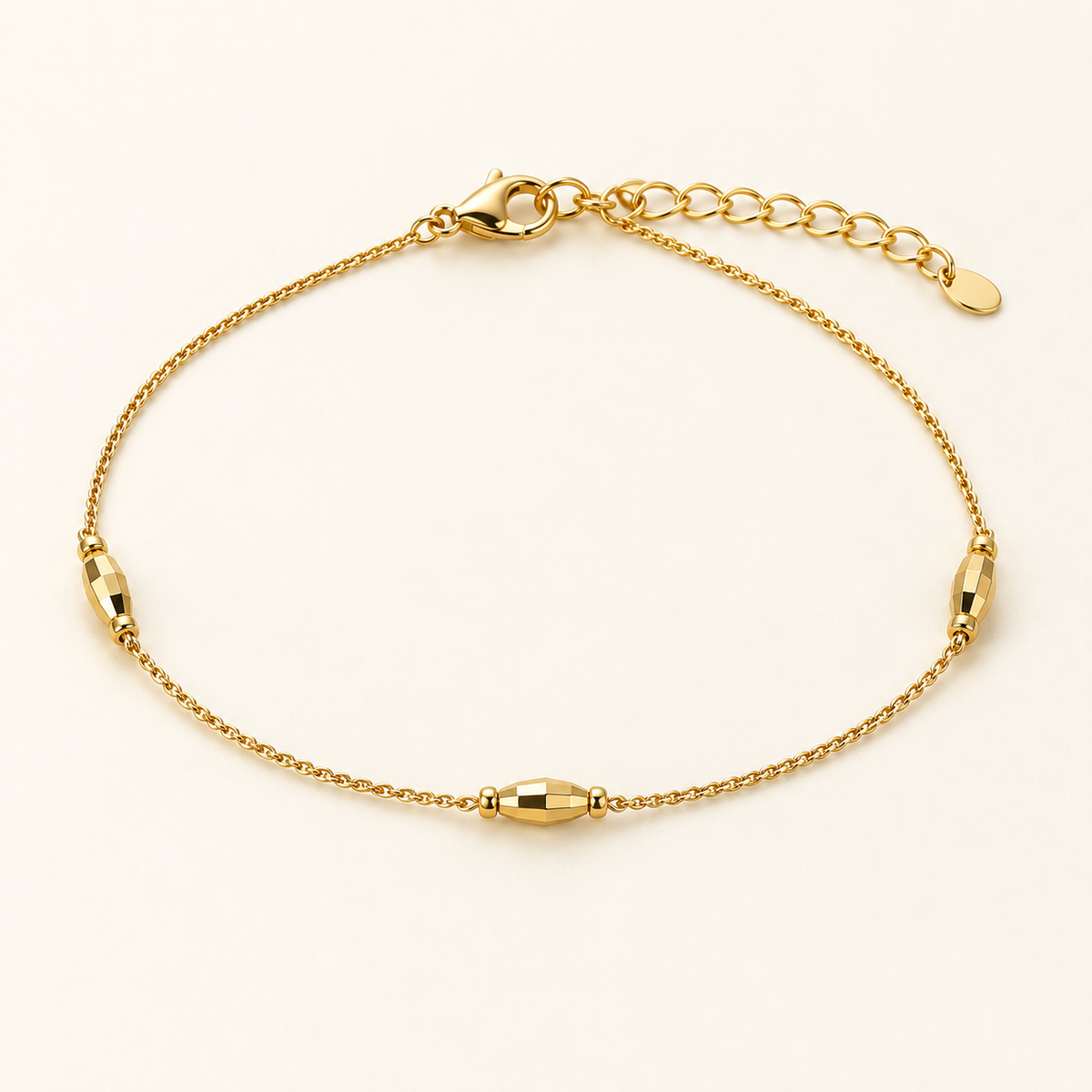 Minimal gold-tone bead chain bracelet with three faceted stations on ivory