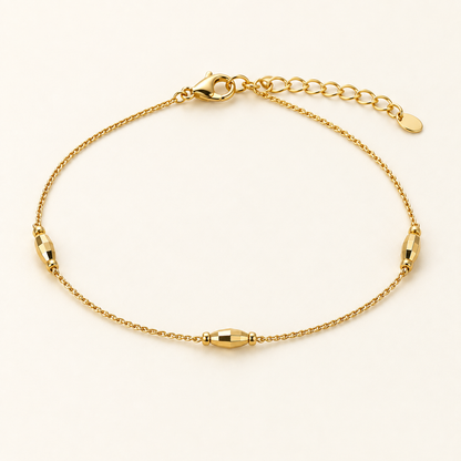 Minimal gold-tone bead chain bracelet with three faceted stations on ivory